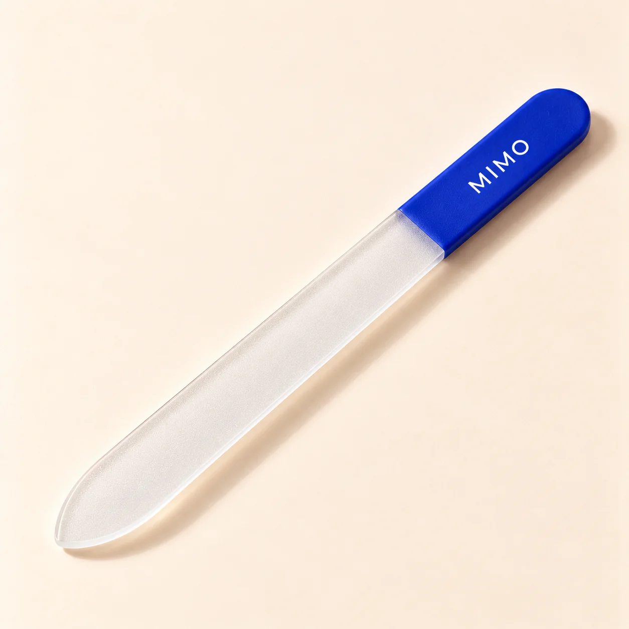 MIMO Glass Nail File with a cobalt grip, lying diagonally on a cream background.