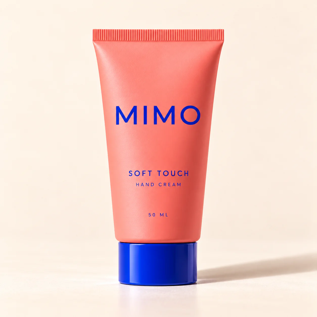 MIMO Soft Touch Hand Cream: a coral squeeze tube with a cobalt cap, standing upright.